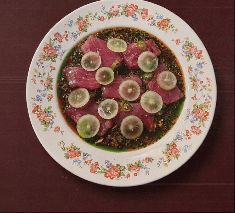 Primer Piso: una tostada de atún servida en un plato floreado sobre una mesa vinotinto.