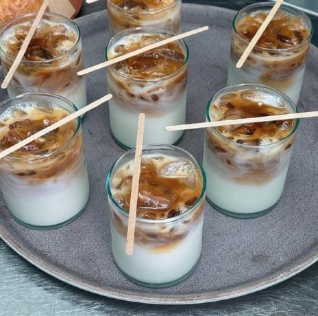 Clus Clus: vasos de café con leche servidos en una bandeja, cada uno con su palito de madera.